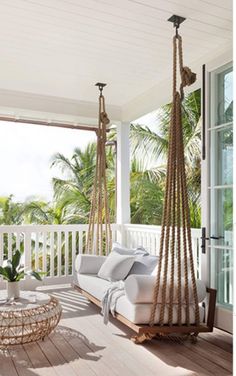 a white porch with two hammocks hanging from it's sides and a couch on the other side