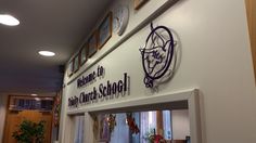 there is a clock on the wall above the entrance to an elementary school that has been decorated