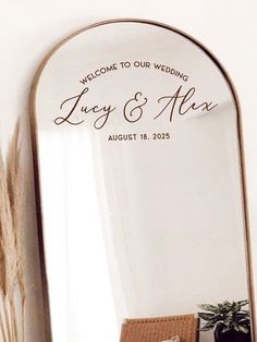 a mirror with the words, welcome to our wedding and an image of a plant on it