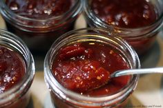 four jars filled with jam sitting on top of a table