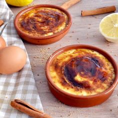 two brown bowls filled with food sitting on top of a table next to lemons