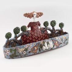 a figurine sitting on top of a blue and white tray filled with trees