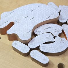 several pieces of paper cut out to look like animals on a wooden surface with holes in the middle