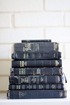 a stack of black books sitting on top of a white table next to a brick wall