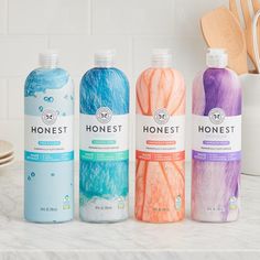 three bottles of honest hand soap sitting on a counter next to wooden utensils