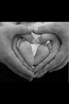 two hands holding a baby's feet in the shape of a heart