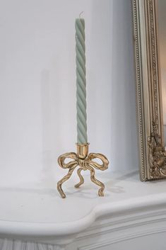 a candle that is on top of a mantle with a mirror in the back ground