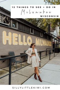 a woman standing in front of a wall with the words hello milwaukee on it