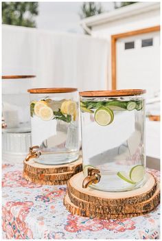 two glass jars filled with lemons and cucumbers on top of a table