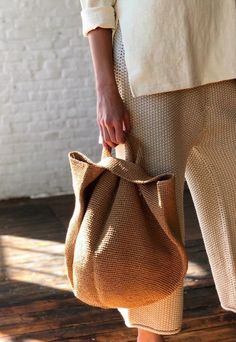 a woman holding a brown bag on top of a wooden floor