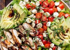 a salad with chicken, tomatoes, avocado and lettuce on it