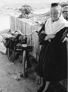 an old woman leaning against a wall next to a bike