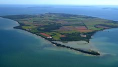 an island in the middle of water with lots of land around it and trees on both sides