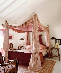 a canopy bed sitting in the middle of a bedroom next to a table and chairs