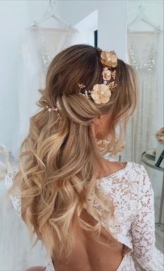 a woman with long blonde hair and flowers in her hair is looking into the mirror