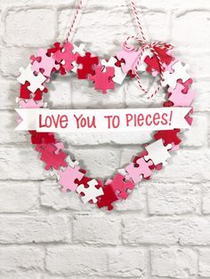 a heart shaped puzzle hanging on a brick wall with the words love you to pieces