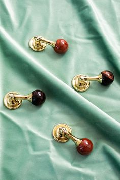 three gold handles with red and black beads on them are sitting on a green cloth