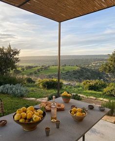 a table with bowls of fruit on it in front of an open air patio area