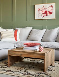 a living room filled with furniture and pillows on top of a wooden coffee table in front of a green wall