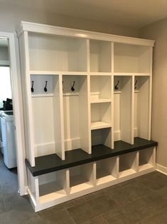 an empty room with white shelves and black benches