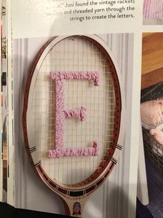 a tennis racquet with the letter e written in pink thread on it's side