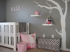 a baby's room with a tree painted on the wall