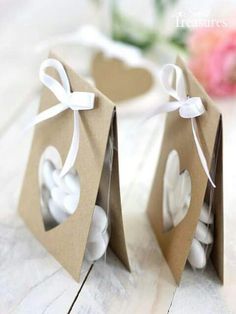 two small brown bags with white hearts on them and a ribbon tied around the top