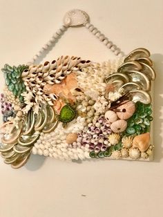 a wall hanging made out of shells and seashells on a white background with beads