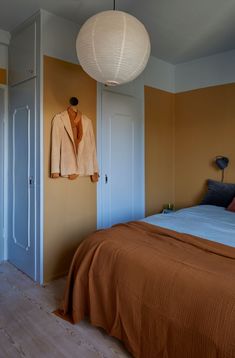 a bed room with a neatly made bed and a hanging jacket on the wall above it