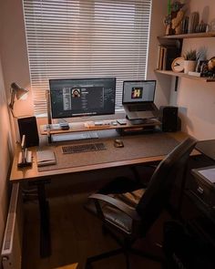 a desk with two computers on it in front of a window