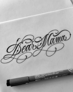 an ink pen sitting on top of a piece of paper with the word dear mama written in cursive writing