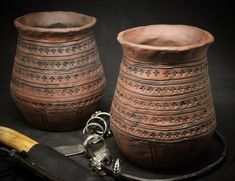 two brown vases sitting on top of a table next to a knife