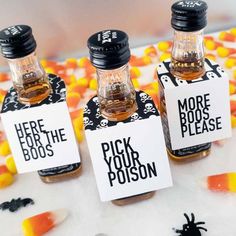 three bottles filled with halloween treats on top of a white table covered in candies