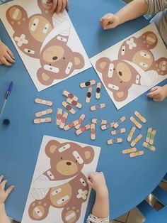 two children sitting at a table with teddy bears cut out of paper and colored pencils