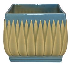 a blue and yellow ceramic planter with long, wavy lines