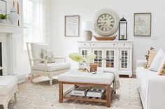 a living room filled with furniture and a clock on the wall above it's fireplace