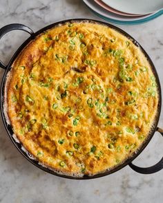 an omelet with green onions and cheese in a cast iron skillet on a marble surface