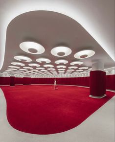 a person standing in the middle of a room with red carpet and round lights on the ceiling