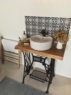 an old sewing machine and sink in a room with white walls, wood flooring and patterned wallpaper