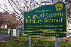 a sign for the longwell green primary school in front of a fenced area