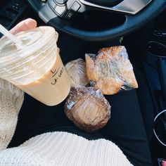 a person holding a drink in their hand next to some bread and other food items