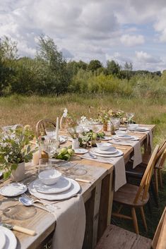 a table set with plates and place settings in the middle of an open field area