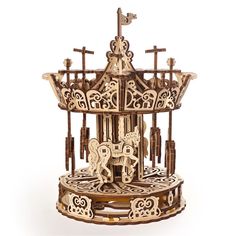 an intricate wooden model of a carousel with horses and crosses on the top, set against a white background