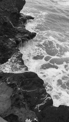 black and white photograph of waves crashing on the rocks at the ocean's edge