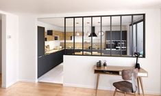 an open kitchen and dining area with wooden flooring, white walls and black framed windows