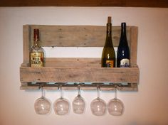 wine glasses and bottles are hanging on a wooden rack