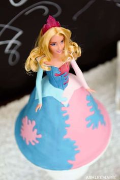 a barbie doll sitting on top of a pink and blue ball