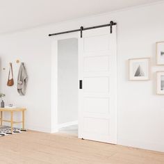 a living room with white walls and wooden flooring next to an open sliding door