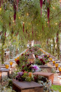 a long table with lots of flowers and greenery hanging from it's ceiling