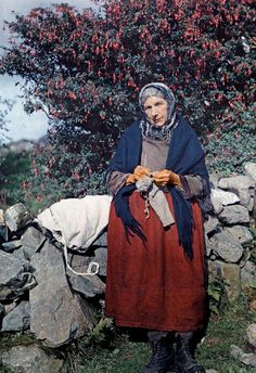 an old woman is sitting on a rock wall